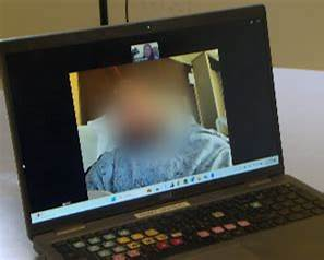 A blurred video interview displayed on a laptop.